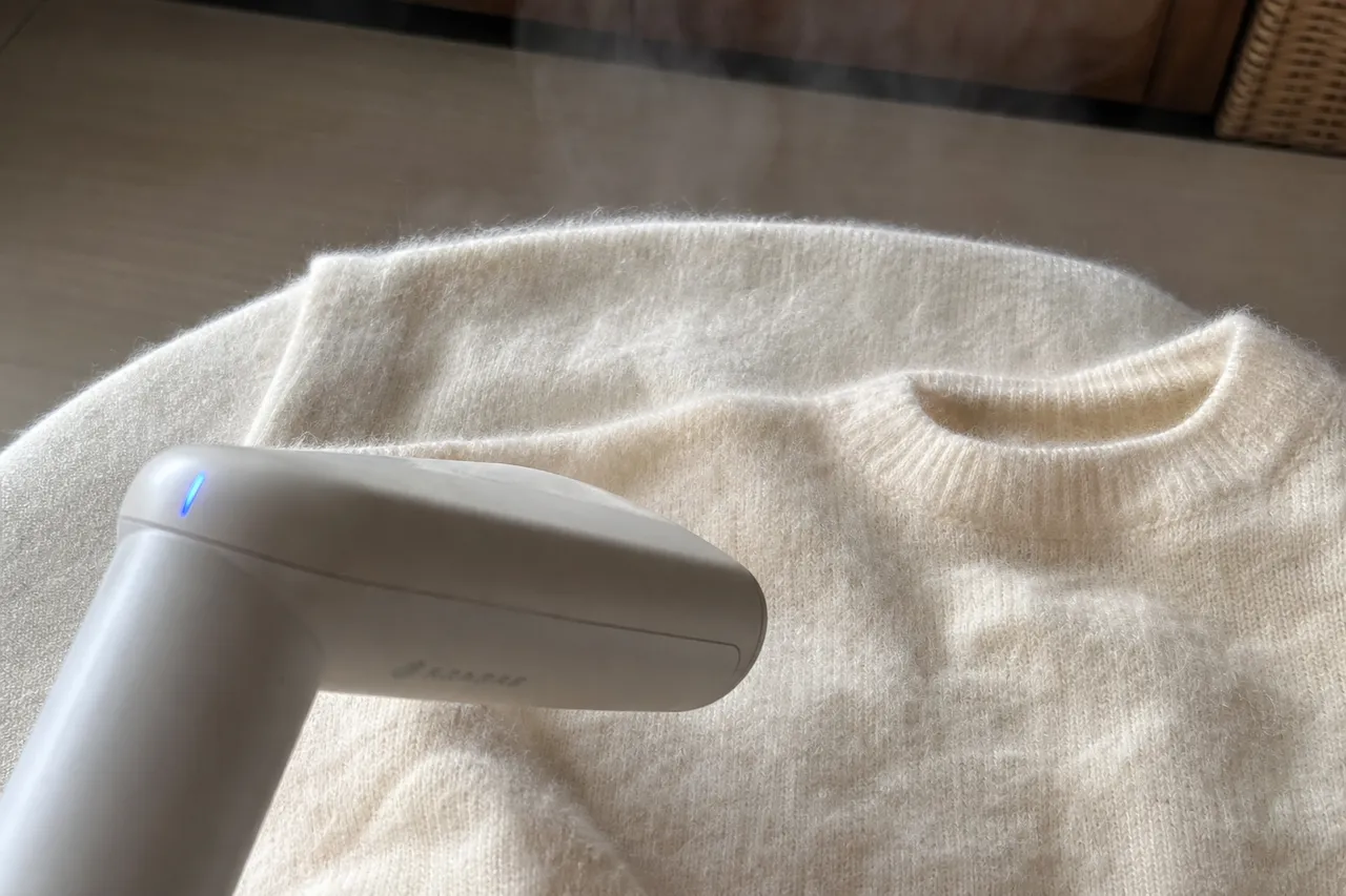 A close-up of a object gently steaming a delicate wool sweater with a handheld steamer, soft steam rising, focus on the fabric texture, clean and organized background, no people, objects and environment only