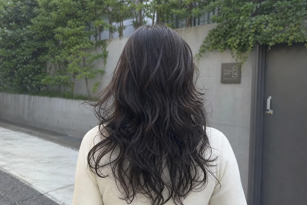 A back view of a object with a layered 'Hush Hippie Perm', showing the light texture and wispy ends, soft outdoor lighting, no people, objects and environment only