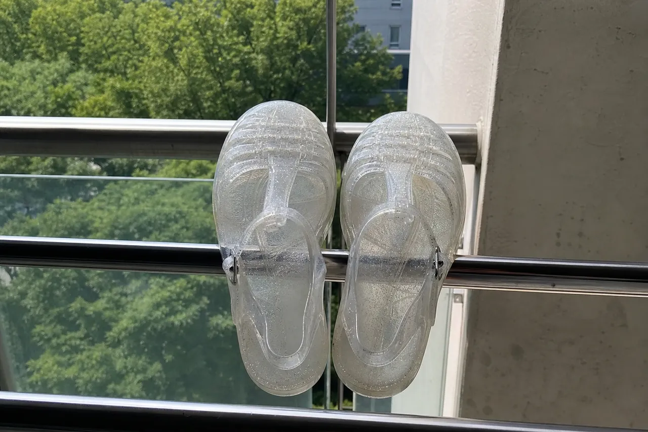 A pair of clean jelly shoes drying in a shaded, well-ventilated balcony, refreshing summer vibe, minimalist photography
