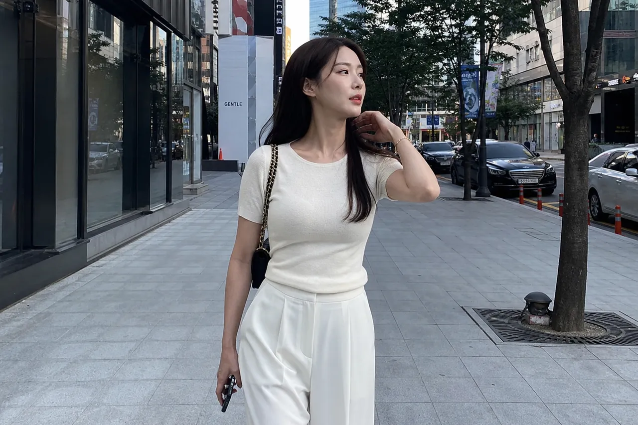 A full-length photograph of a stylish Korean woman with a slim and toned physique, wearing a minimalist yet sophisticated outfit, walking on a modern city street, soft natural afternoon light, high fashion editorial style