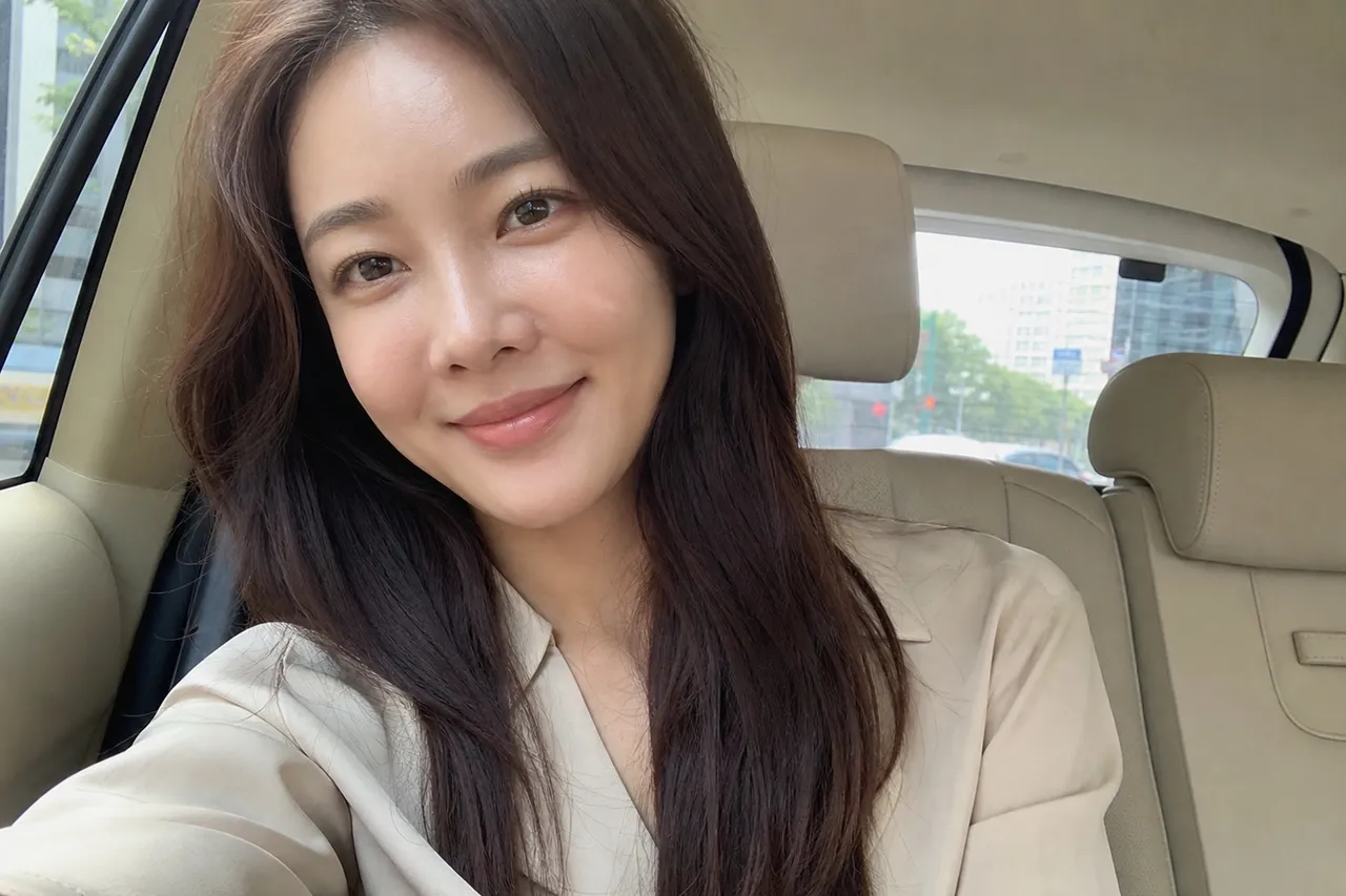 A sophisticated photograph of a Korean woman in her 30s wearing a minimalist beige silk blouse, looking serene with a gentle smile, soft natural lighting, high-end fashion magazine style
