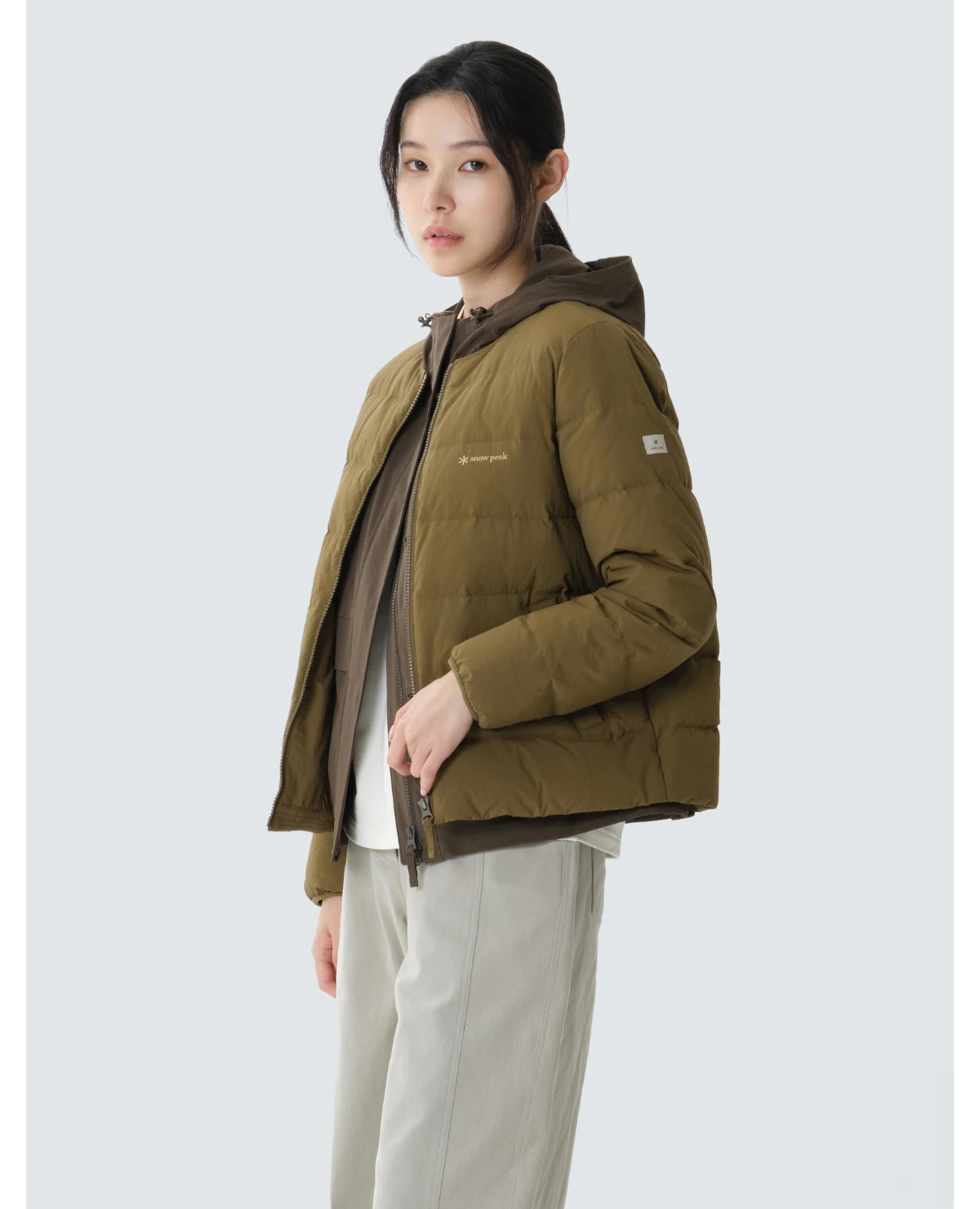 옐로우 카키 컬러의 스노우피크 랜드 경량 다운 자켓이 옷걸이에 걸려 있는 깔끔한 모습