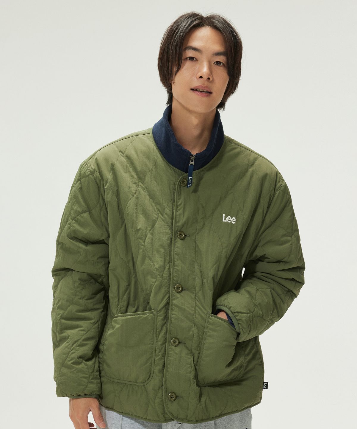 침대 위에 리버서블 라이너 자켓 카키 제품을 펼쳐놓고 전체적인 실루엣과 카키 컬러감을 보여주는 사진