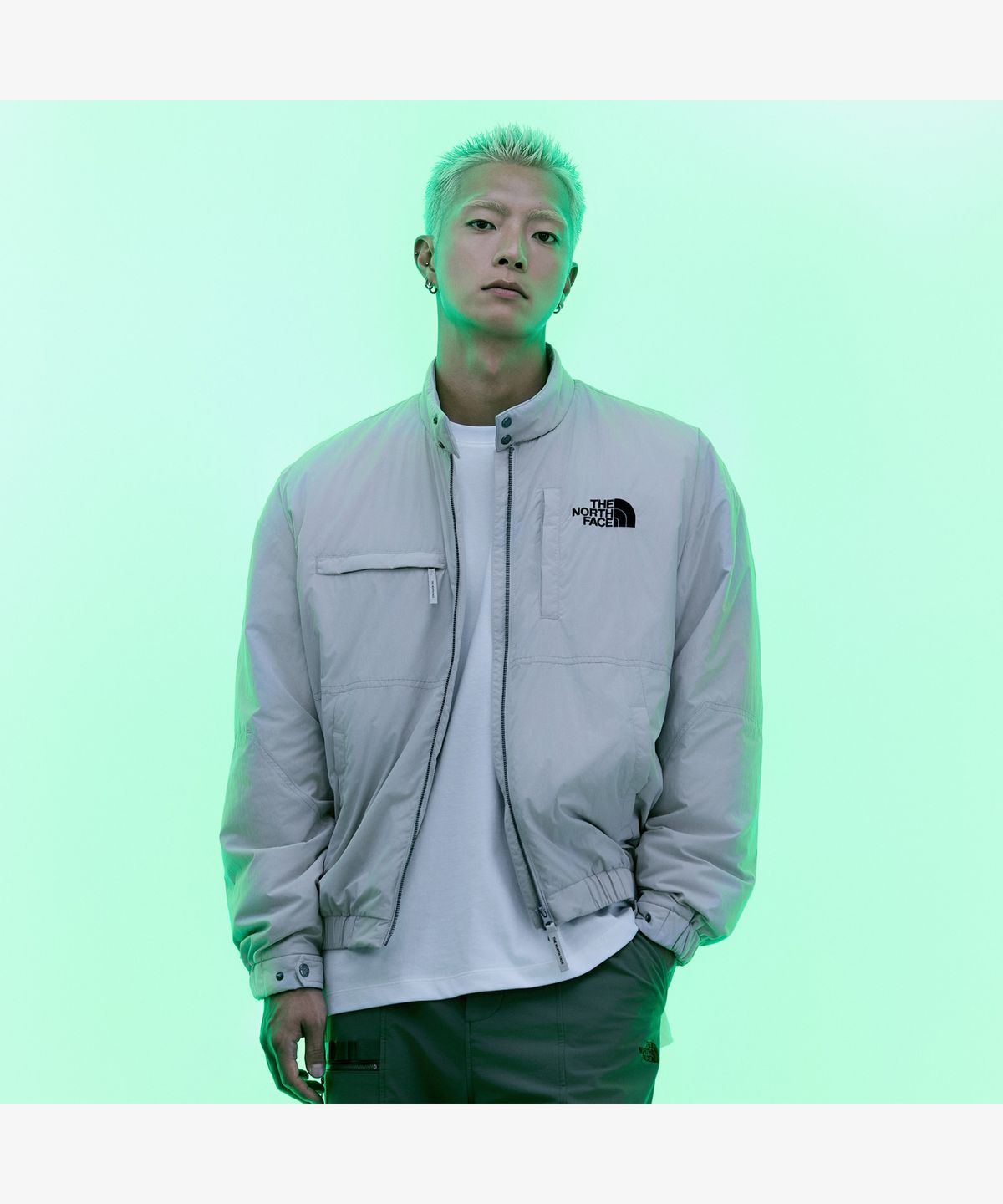 깔끔한 화이트 샌드 컬러의 노스페이스 봄버 재킷이 침대 위에 놓여 있는 모습