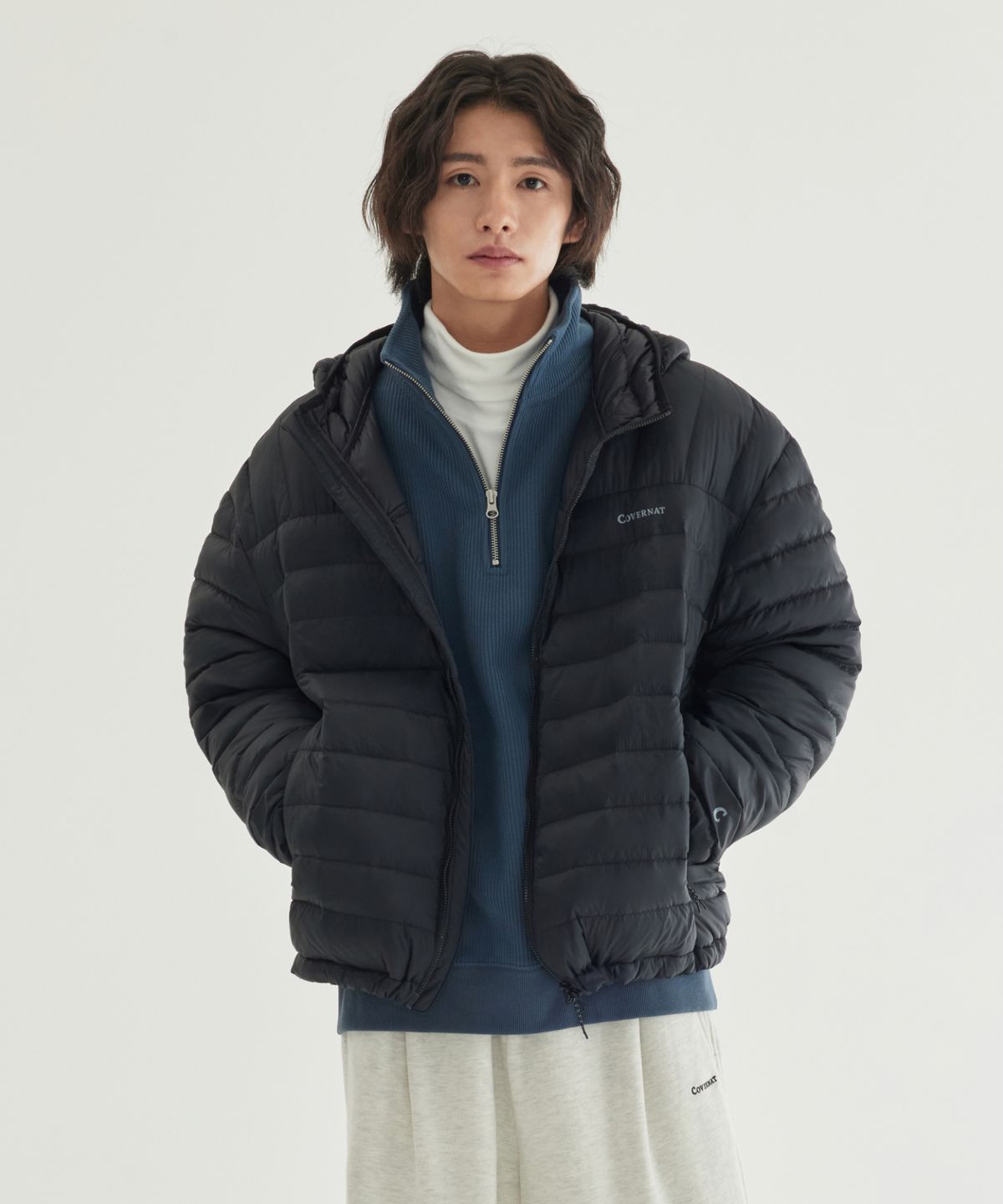 사무실 의자에 걸쳐둔 블랙 경량 패딩의 매트한 질감과 로고 자수 근접샷
