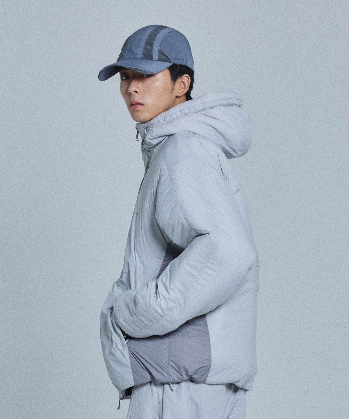 깔끔한 그레이 컬러의 노드랩스 패딩 자켓이 침대 위에 놓여있는 모습