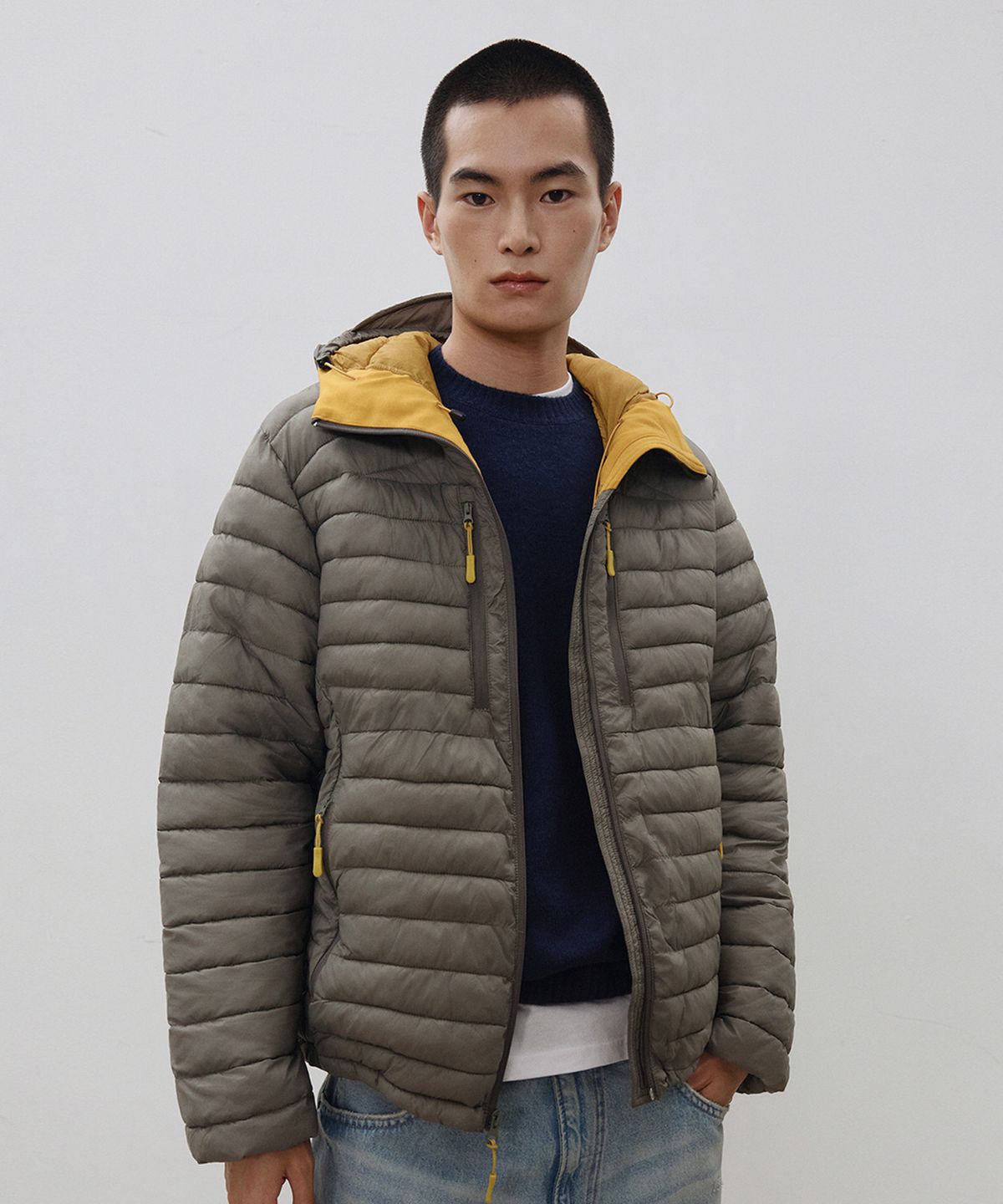 178cm 남동생이 그레이쉬 카키 패딩을 입고 청바지와 매치해 야외에서 활동적인 포즈를 취하고 있는 전신 샷