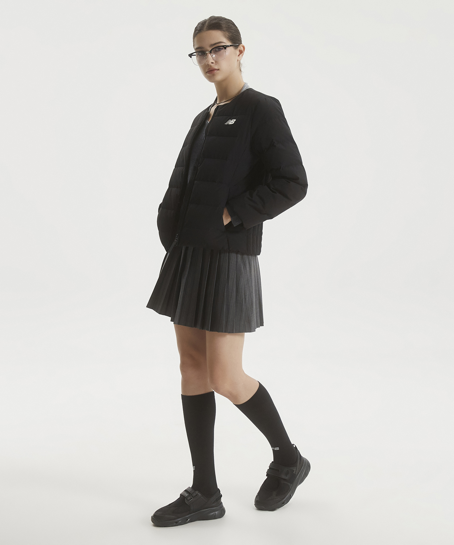 깔끔한 블랙 컬러의 뉴발란스 WOMEN 액티브 라이트 다운을 침대 위에 펼쳐놓은 전체적인 모습