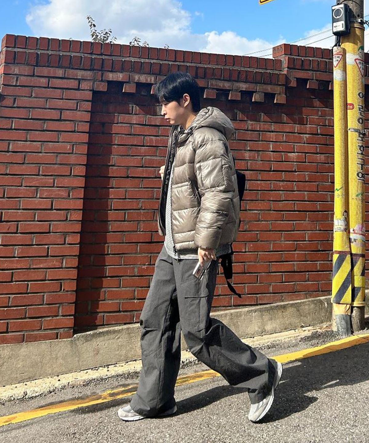 178cm 남성이 후드를 쓰고 야외에서 활동적인 포즈를 취한 전신샷, 진그레이 컬러의 오묘한 광택이 돋보이는 장면