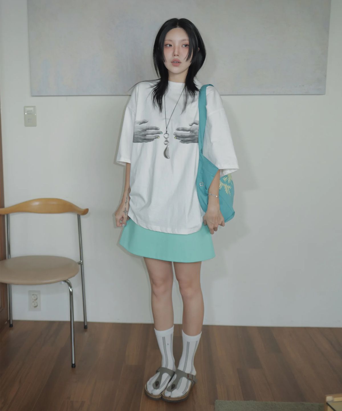베이지색 에코백을 어깨에 메고 노트북 파우치를 손에 든 채 카페로 향하는 자연스러운 모습