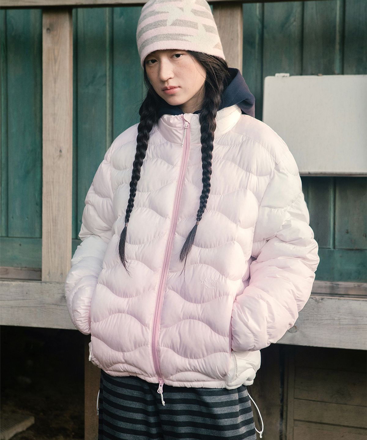 바람 부는 야외에서 하이넥 지퍼를 끝까지 올리고 주머니에 손을 넣은 채 걷고 있는 생생한 모습