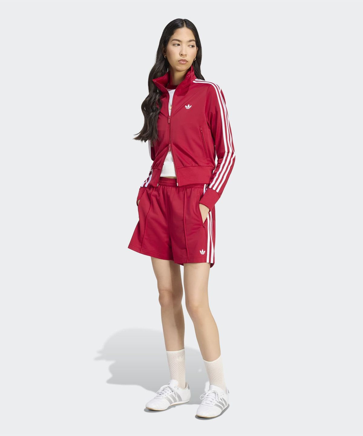 방 바닥에 바지를 펼쳐놓고 흰색 삼선 라인과 아디다스 불꽃 로고 디테일을 근접 촬영한 사진